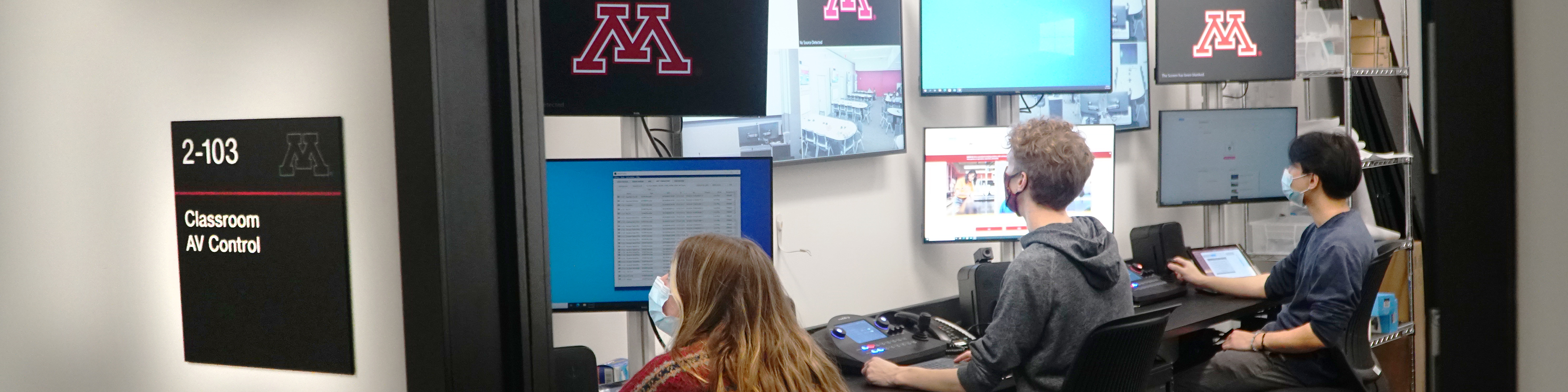 3 student staff managing classrooms at stations in a control booth