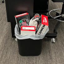 Overflowing office trash bin in a classroom