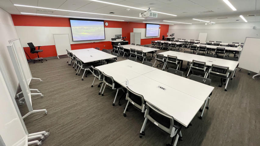 8 pods of 8 chairs in a combined room with two projection screens and whiteboards